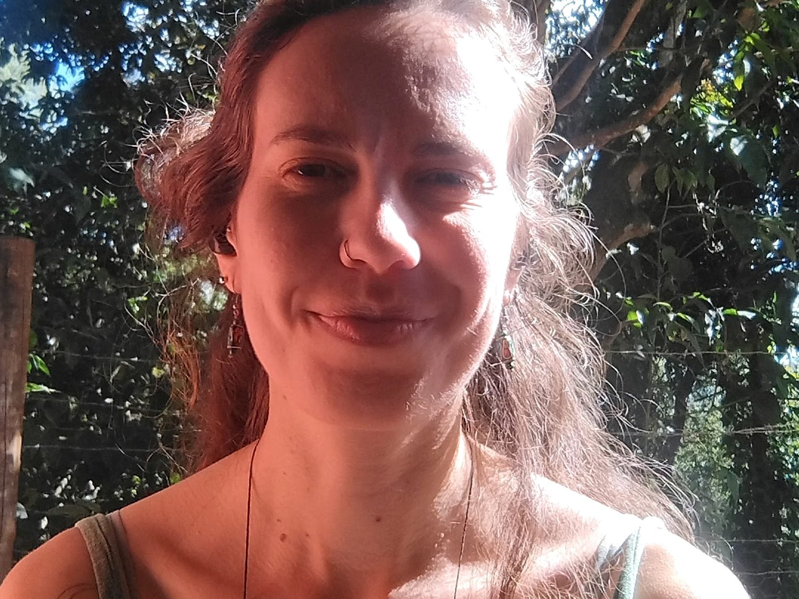 Carol Reymunde em área externa com árvores ao fundo